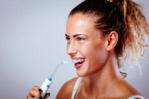 A person demonstrating how to floss with braces, showing proper technique for cleaning between brackets and wires.